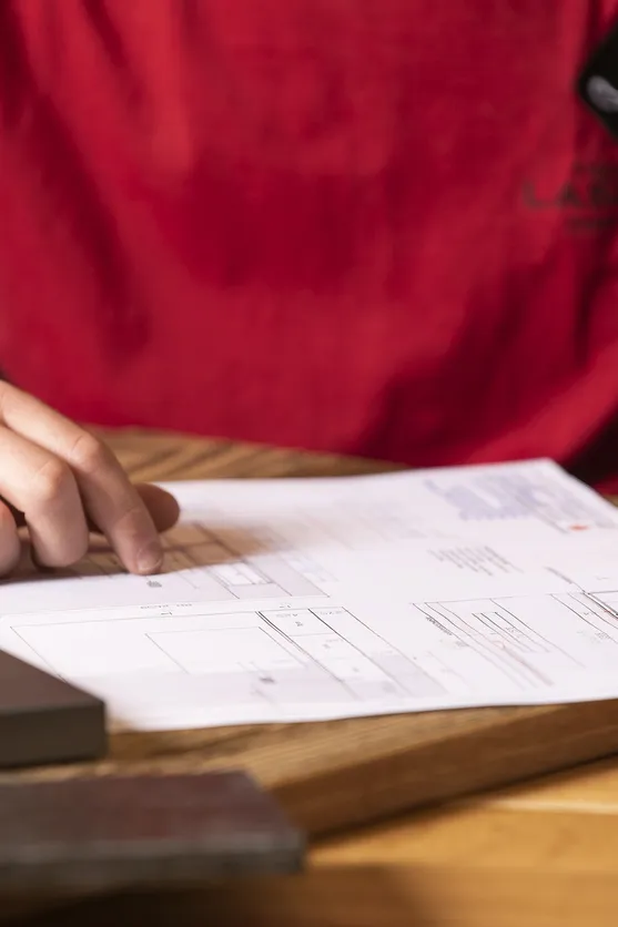 Zwei Personen besprechen technische Zeichnung auf Holzschreibtisch