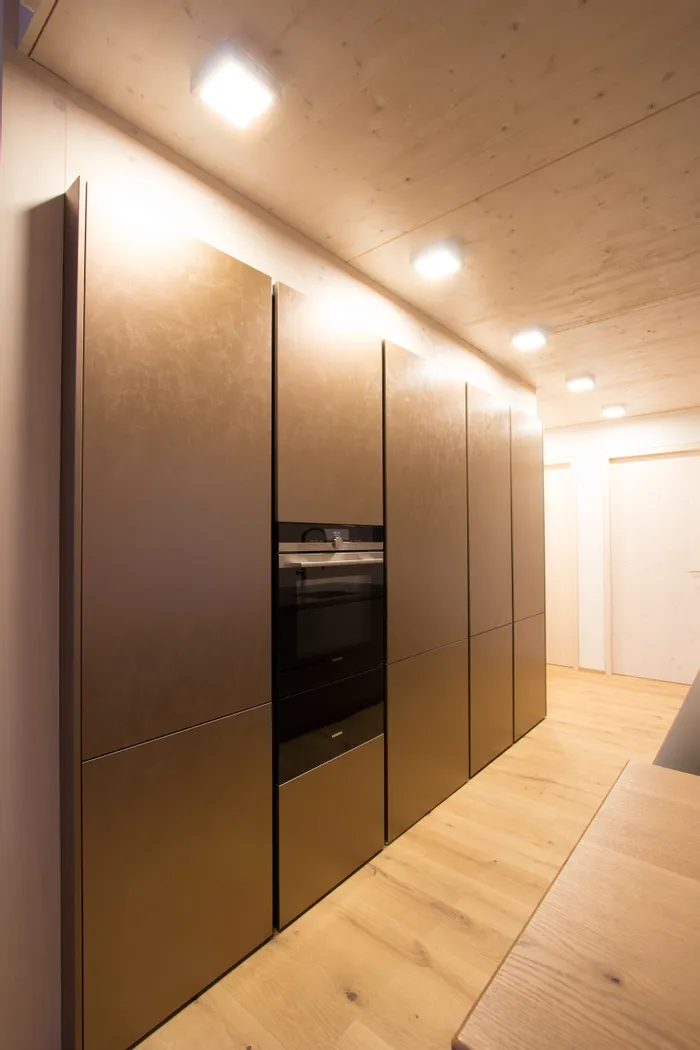 Moderne Einbauküche mit bronzefarbenen Schränken und integriertem Backofen