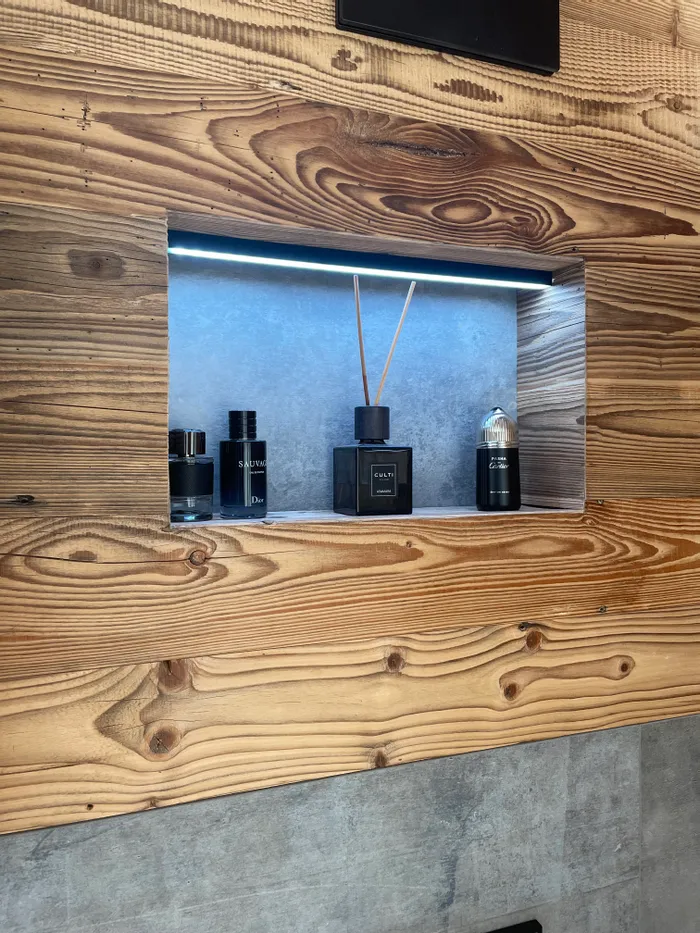 Moderne Parfüm- und Raumduftflakons in einem Holzregal mit LED-Beleuchtung