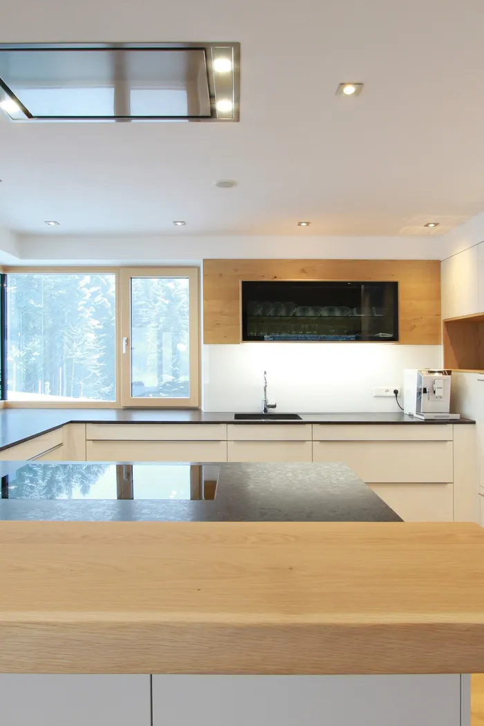 Moderne Einbauküche mit weißen Fronten, Holzarbeitsplatte und großen Fenstern