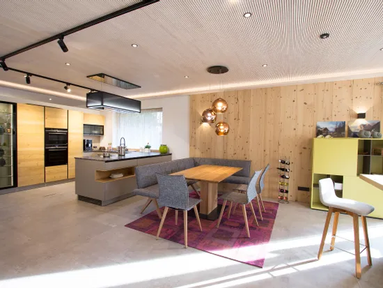 Moderne offene Wohnküche mit Holzelementen, Kücheninsel, Esstisch und stilvollen Lampen