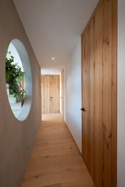 Moderner Flur mit Holztüren, Parkettboden und rundem Wanddurchbruch mit Pflanzen