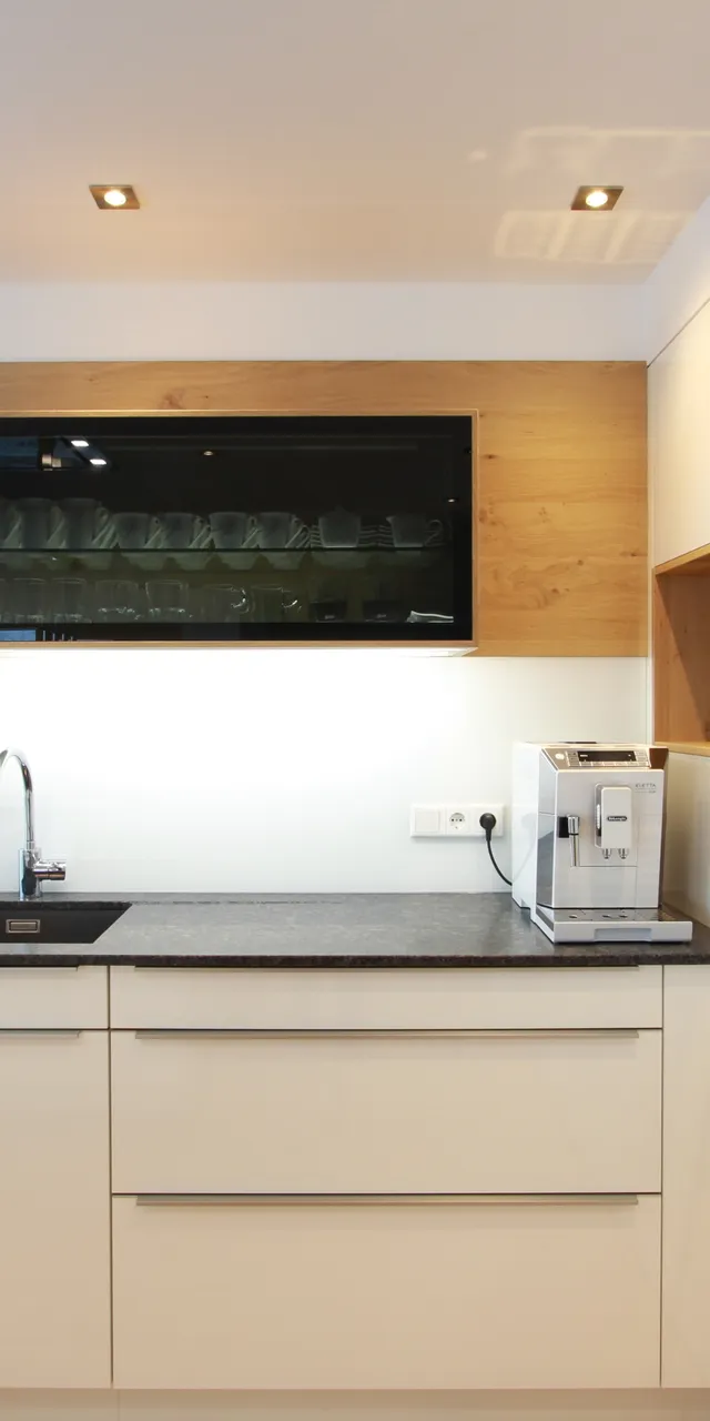 Moderne weiße Einbauküche mit Kaffeemaschine, Obstschale und großem Fenster