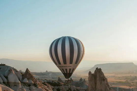 Heißluftballon fliegt über Felsformationen in Kappadokien bei Sonnenaufgang