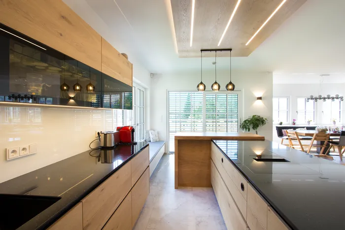 Moderne offene Küche mit Holzfronten, schwarzen Arbeitsplatten und Hängelampen