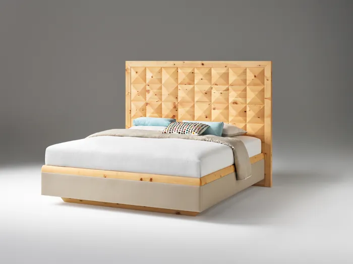 Modernes Bett mit gepolstertem Rahmen und geometrischem Holzkopfteil vor grauem Hintergrund
