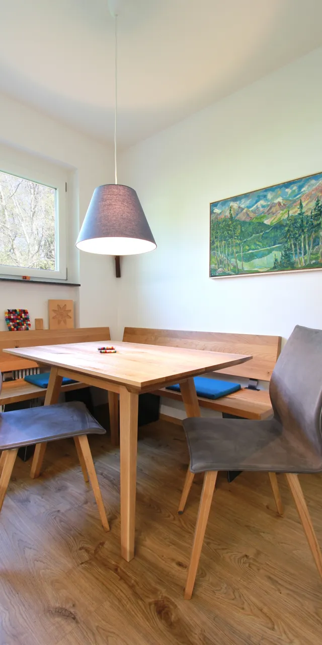 Moderne Essecke mit Holztisch, grauen Stühlen und Landschaftsbild an der Wand