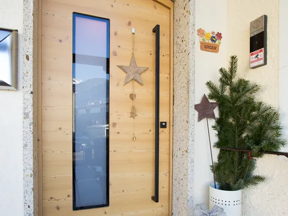 Holzeingangstür mit Weihnachtsdeko, Geschenk, Fussmatte und kleiner Tanne daneben