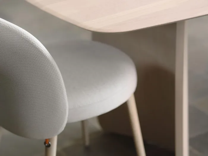 Moderner heller Holzschreibtisch mit grauem Polsterstuhl und gestapelten Magazinen