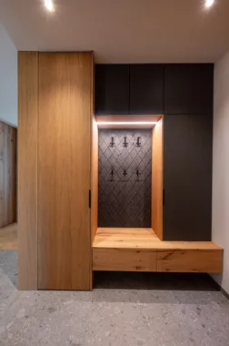 Moderne Garderobe aus Holz mit dunklen Schrankfronten und beleuchteter Sitznische