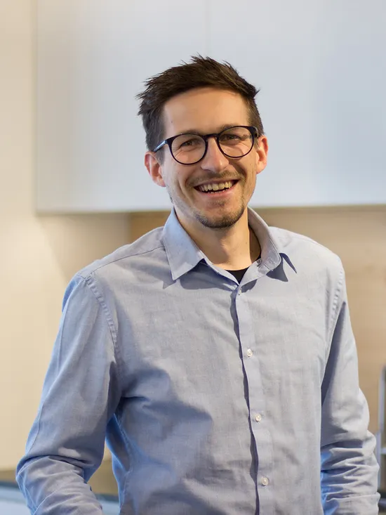 Lächelnder Mann mit Brille und Hemd steht in moderner Küche