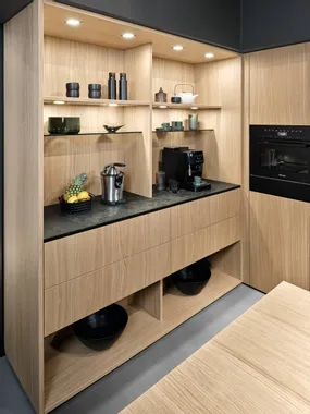 Moderne Küchenzeile mit Holzfronten, schwarzen Geräten und eingebauten Regalen