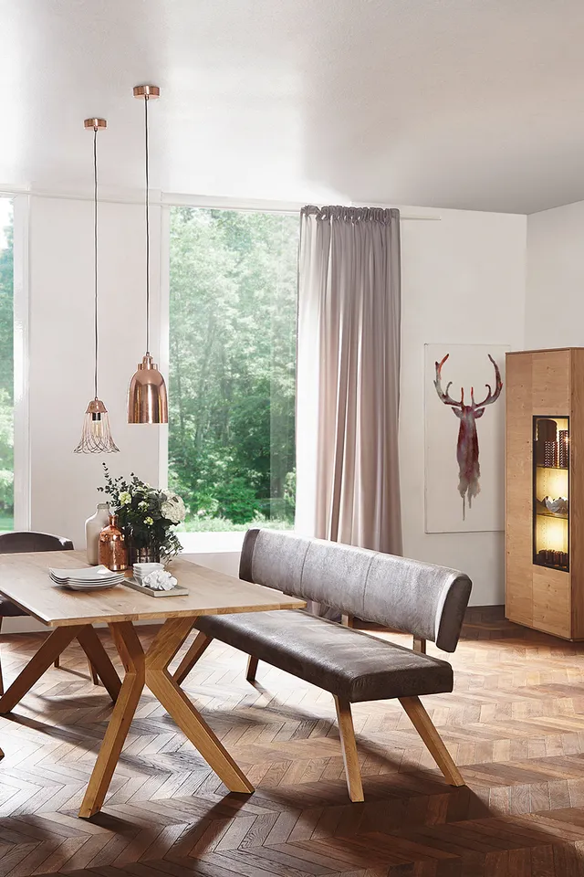 Modernes Wohnzimmer mit Holzmöbeln, Esstisch, Fernseher und großen Fenstern mit Blick ins Grüne