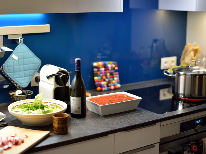 Moderne Küche mit Salatschüssel, Weinflasche, Auflaufform und Kochtopf auf dem Herd