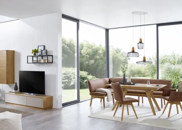 Modernes Wohnzimmer mit Holzmöbeln, Eckbank und großen Fenstern mit Blick ins Grüne